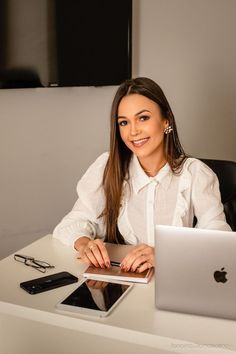 a woman sitting at a desk in front of a laptop computer and cell phone on her lap