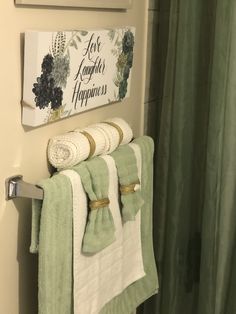 towels are hanging on the towel rack next to a green shower curtain in a bathroom