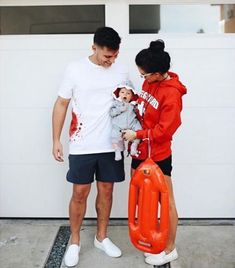 a man and woman standing in front of a garage door holding an orange life preserver