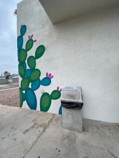 a mural on the side of a building with a cactus painted on it's side