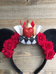 a mickey mouse ears headband with red roses and a crown on it's head