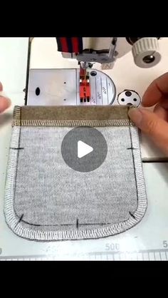 someone is using a sewing machine to sew a small pouch on a piece of fabric