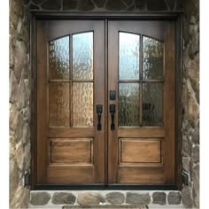 two double doors with glass on each side and stone wall behind them in front of a house