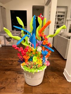 a potted plant filled with lots of different colored plastic toys on top of a wooden floor