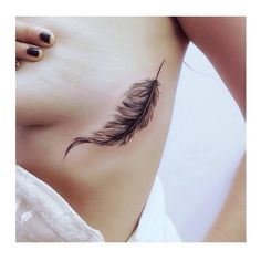 a woman's stomach with a feather tattoo on it