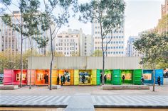 a group of people standing in front of colorfully painted shipping containers on the side of a street