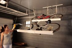 a woman is looking at two bikes hanging from the ceiling