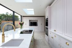 a large kitchen with white cabinets and gold faucet pulls out from the center island