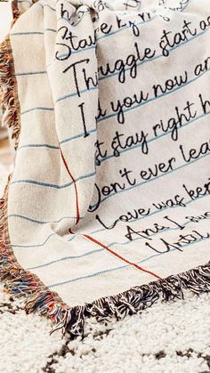 a blanket with writing on it sitting on top of a white rug next to a wooden table