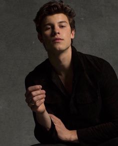 a young man sitting down with his hands folded