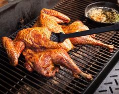 chicken being cooked on the grill with tongs