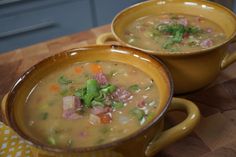 two yellow bowls filled with soup sitting on top of a wooden table next to each other