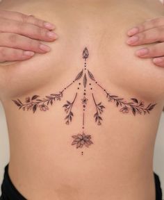 a woman's lower back tattoo with leaves and beads on her stomach, showing the side