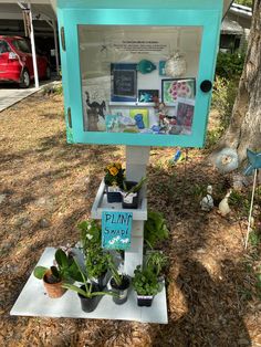 a blue and white box with plants in it sitting on the ground next to a tree