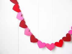 a red and pink heart shaped garland hanging on a white wall