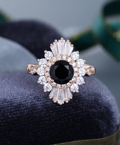 a black diamond ring sitting on top of a velvet cushion