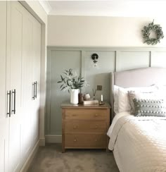 a bedroom with a bed, dresser and plants on the nightstands next to it