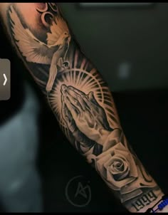 a person with a tattoo on their arm holding a cross and praying hands in front of them