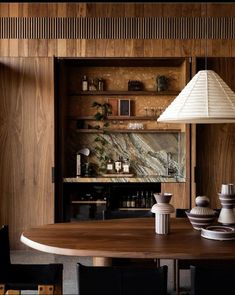 a dining room table with two vases on it and a lamp in the corner