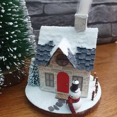 a snowman is standing in front of a small house