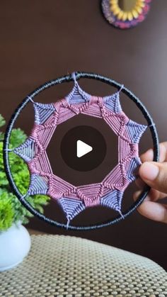 a person holding up a circular object made out of crochet