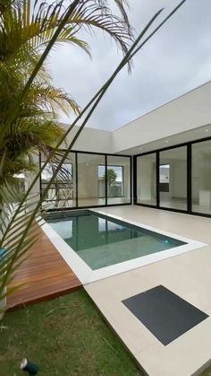 an empty swimming pool in the middle of a yard with grass and palm trees around it