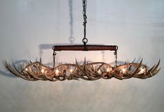 a chandelier with deer antlers hanging from it's sides and four lights on each side