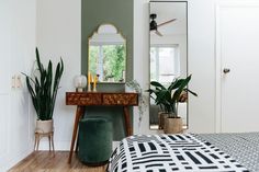 a bedroom with a bed, mirror and plant on the dresser in front of it