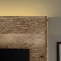 a bed with a wooden head board next to a framed photograph on the wall above it