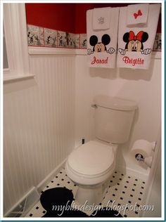 a bathroom with mickey mouse towels hanging on the wall and a toilet in the corner