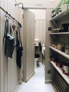 a narrow hallway with open shelving and hanging clothes on the rack, along with other items