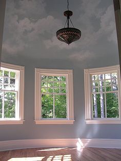 an empty room with three windows and a chandelier