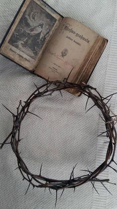 an open book with a crown of thorns on top of it