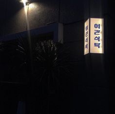 the sign is lit up at night in front of a building with lights on it