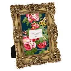 an ornate gold frame with pink and yellow flowers painted on the front, along with a name tag