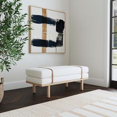 a white bench sitting in front of a painting on the wall next to a potted plant