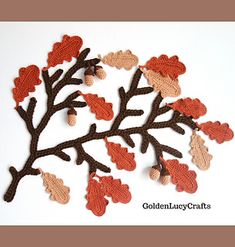 crocheted leaves and acorns are arranged on a white surface with the words autumn written below them