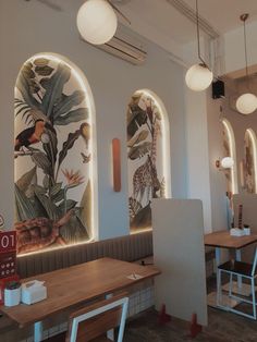 the inside of a restaurant with tables, chairs and artwork on the wall behind them