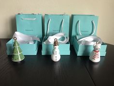 three snowmen are sitting in small boxes with ribbons on the top and one has a christmas tree ornament