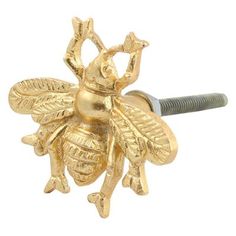 a gold colored metal bee on a white background