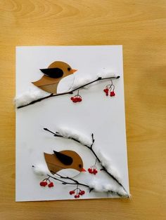 two birds sitting on top of a tree branch with berries in the branches and snow