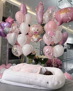 there is a bed with pink and white balloons hanging from the ceiling