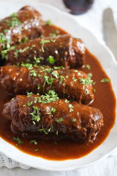 meatballs covered in gravy and garnished with parsley on a white plate