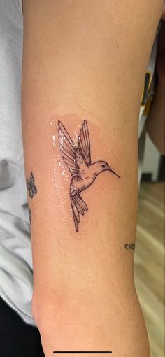 a tattoo on the arm of a woman with a hummingbird in it's beak