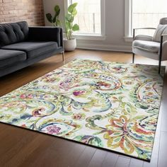 a living room filled with furniture and a rug on top of a hard wood floor