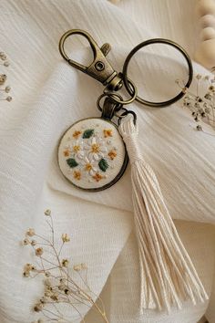 a keychain with flowers and tassels on top of a white cloth