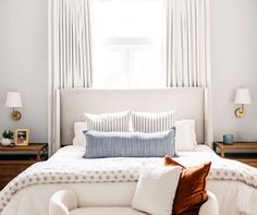 a white bed sitting under a window in a bedroom