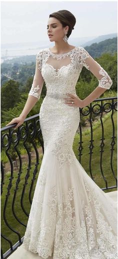 a woman standing on top of a balcony next to a railing wearing a wedding dress