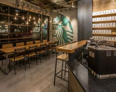 a starbucks coffee shop with many tables and chairs in front of the counter, along with lots of lights