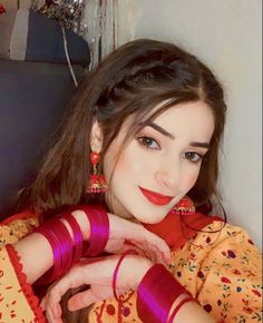 a woman with long dark hair wearing red and gold jewelry is posing for the camera